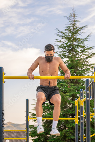 Strong young latin man doing calisthenics with mask