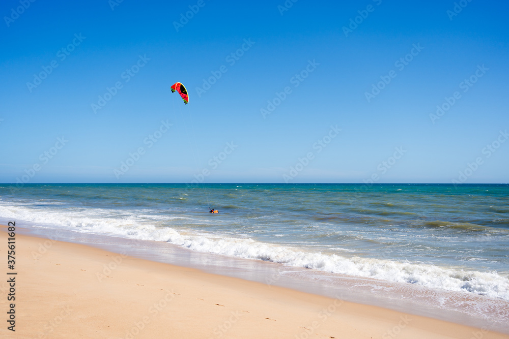 Beautiful kiteboarding surfing with golden sand sea water. Kite in the air on the beach, sunny outdoors background. Beautiful kiteboarding surfing with golden sand sea water. Kite in the air on the beach, sunny outdoors background.