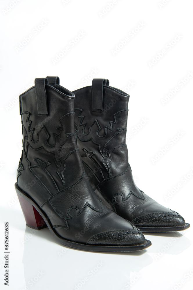 Fashionable female black leather cowboy boots isolated on a white background.
