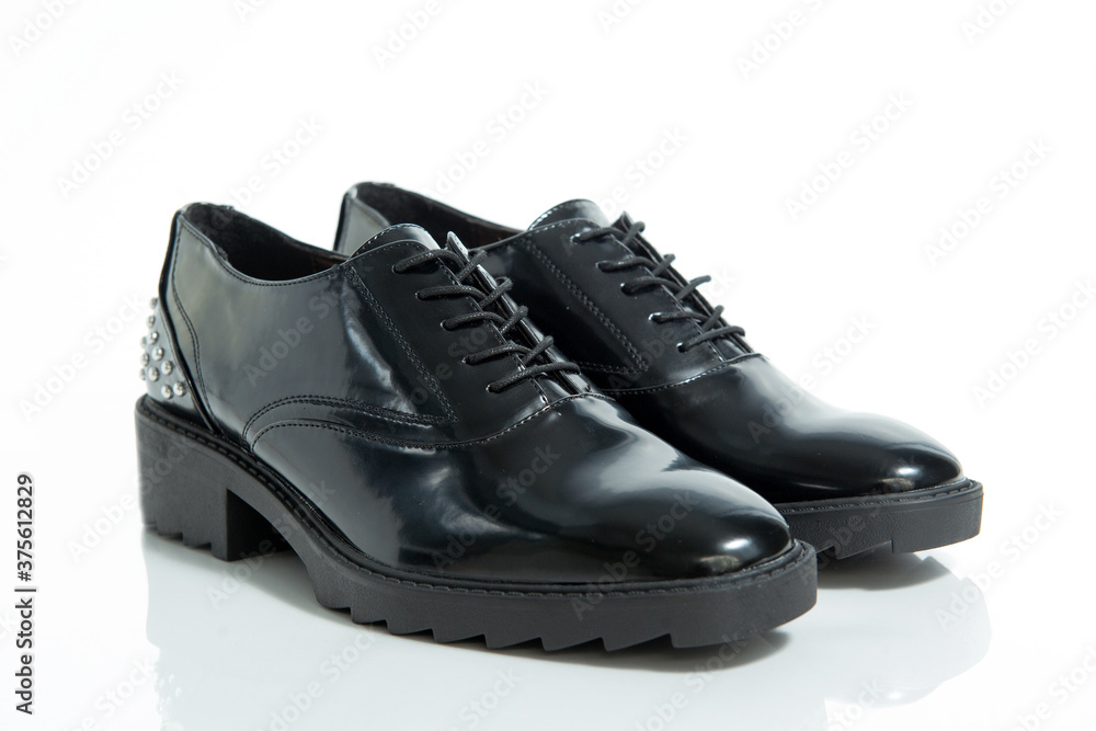 Fashionable female black leather shoes with silver details isolated on a white background.