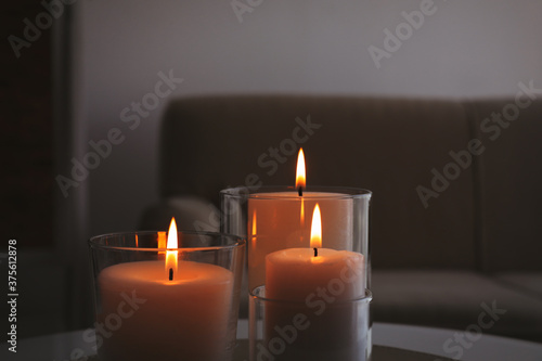Burning candles in glass holders indoors  closeup