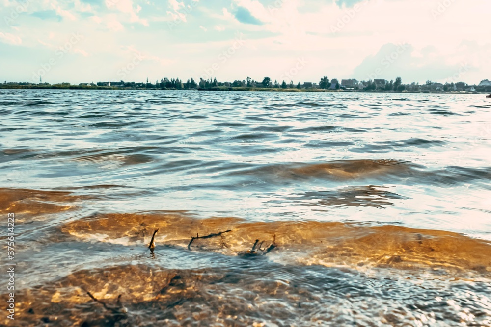 Obraz premium Waves of the city lake with dirty yellow water. Bathing is forbidden.
