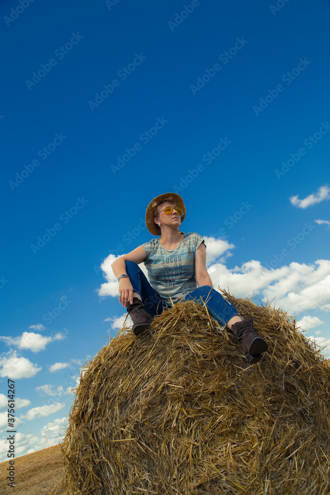 A woman in cowboy hat and yellow sunglasses with wheat rolls A woman in cowboy hat and yellow sunglasses with wheat rolls