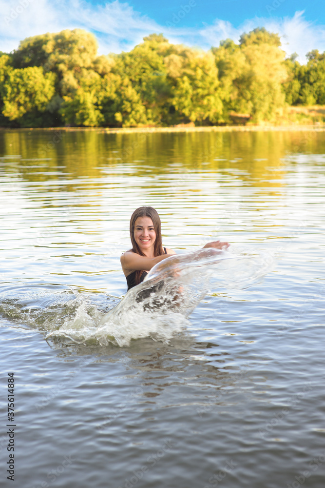 Fototapeta premium young beautiful woman in swimsuit in water splashing and laughing, happy vacation