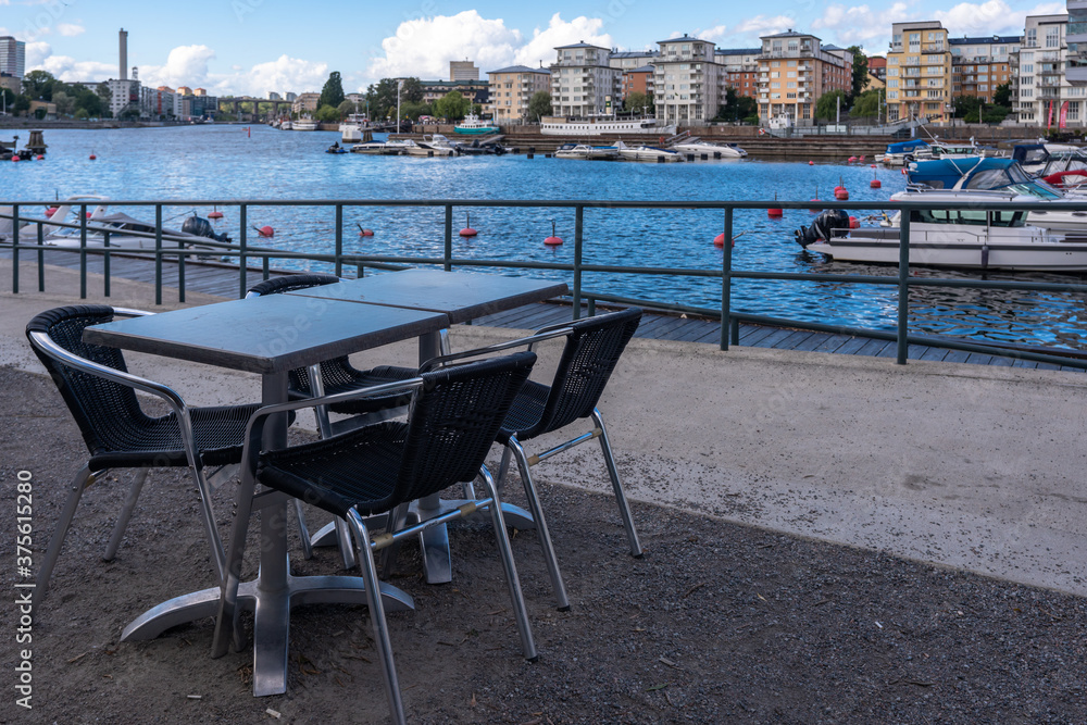 Summer cafe on the waterfront in Stockholm. There are no visitors. Empty tables and chairs. Panoramic view of the new modern district Summer cafe on the waterfront in Stockholm. There are no visitors. Empty tables and chairs. Panoramic view of the new modern district
