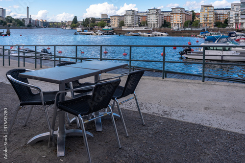 Summer cafe on the waterfront in Stockholm. There are no visitors. Empty tables and chairs. Panoramic view of the new modern district "Henriksdal" of Stockholm on the lake Hammarby. 