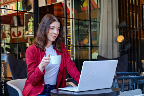 Portrait of young beautiful woman using laptop connected to coff