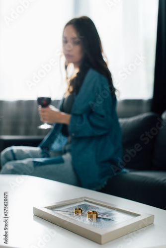 selective focus of golden rings on photo frame with broken glass near brunette woman   divorce concept