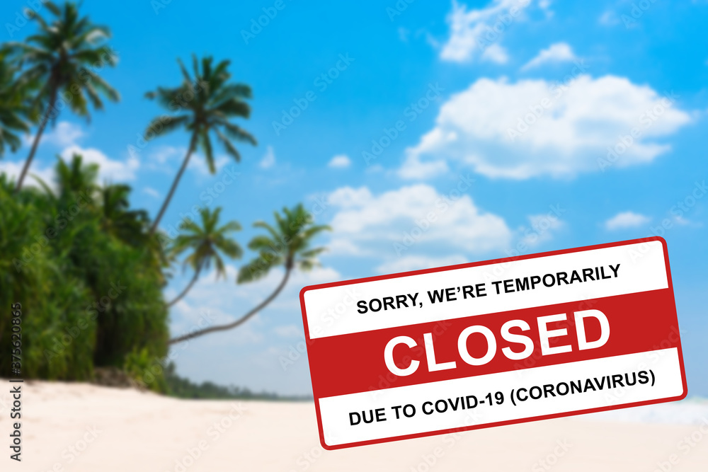 Coconut palm trees at tropical beach on island resort closed due to Coronavirus Covid-19 sign