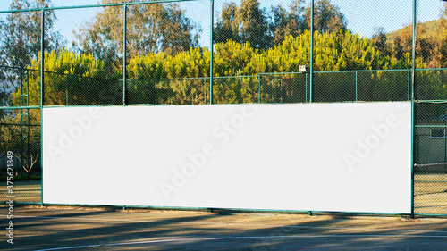 large blank white poster with mockup space hanging on metal fence of play ground photo