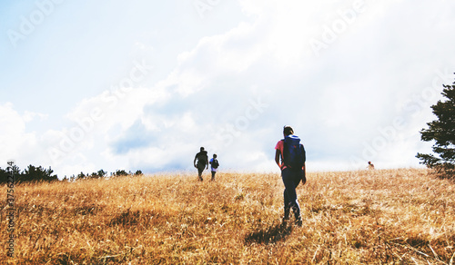 Rear view of unrecognizable people with backpack hiking in the n