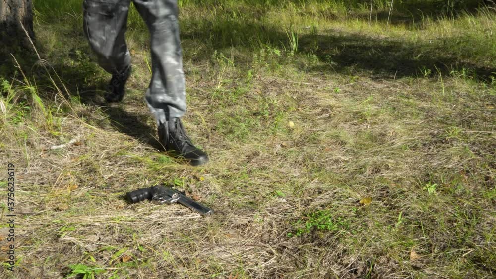 A military man in a camouflage protective uniform walks through the woods and finds a revolver loaded with cartridges. A deserter soldier in a forest area. Military in military uniform with a gun. A military man in a camouflage protective uniform walks through the woods and finds a revolver loaded with cartridges. A deserter soldier in a forest area. Military in military uniform with a gun.