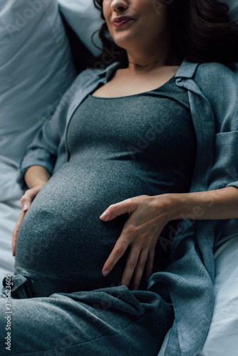 cropped view of pregnant woman suffering from pain on bed