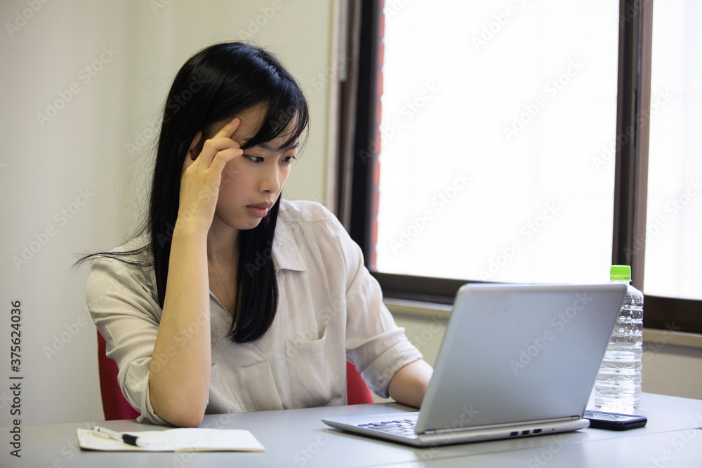 ノートPC画面を見て考えている若い女性 ノートPC画面を見て考えている若い女性