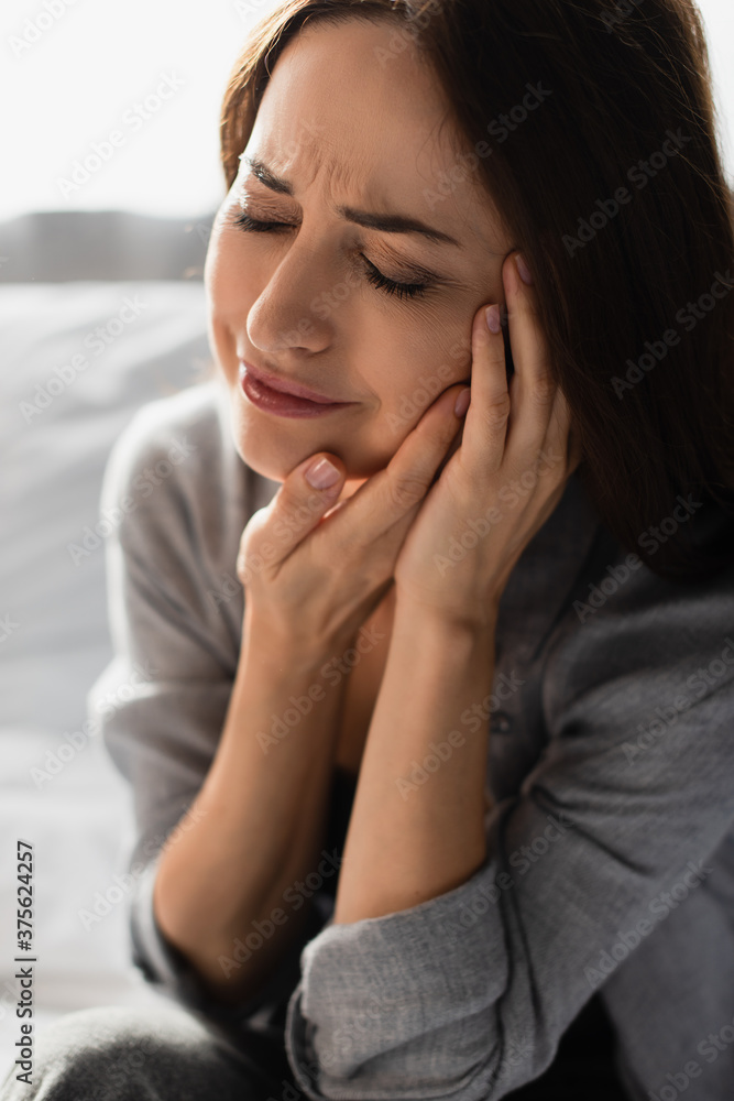 brunette woman with closed eyes touching face while suffering from toothache at home brunette woman with closed eyes touching face while suffering from toothache at home