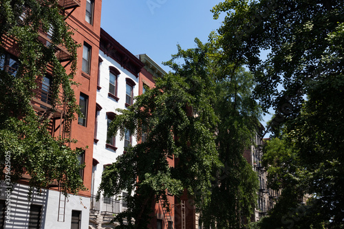 Row of Colorful Old Residential Buildings in the East Village of New York City with Fire Escapes and Green Trees during Summer