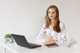 Young female sitting in front of laptop smiling, working from home