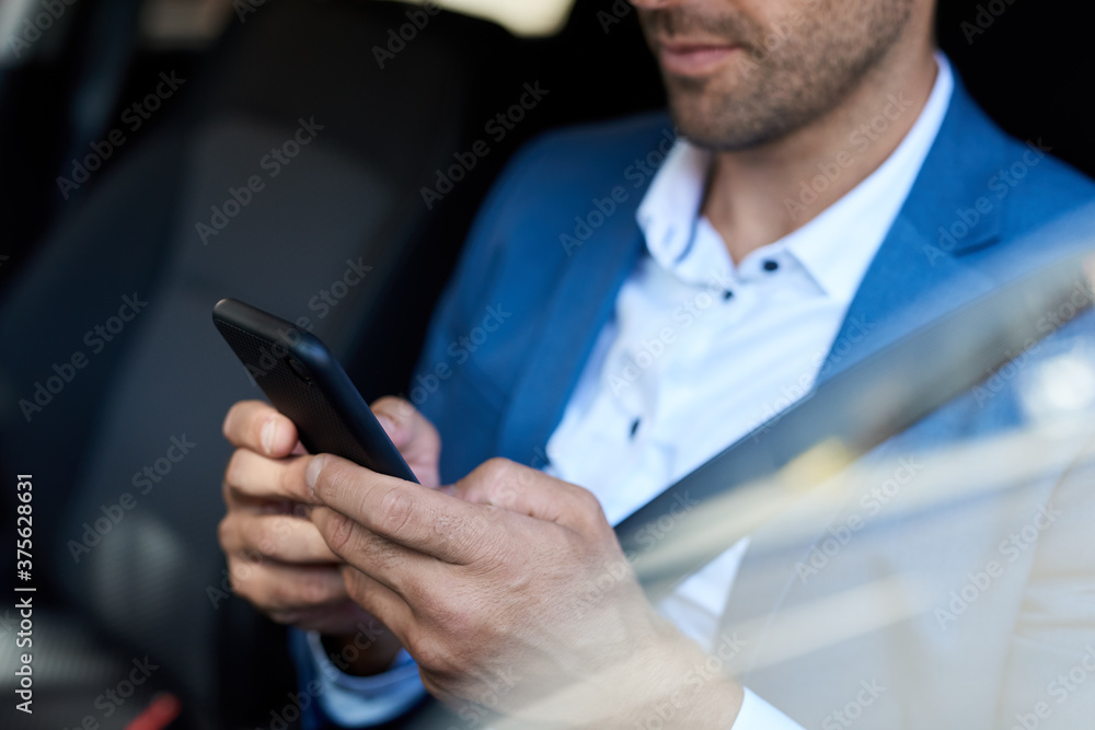 Man sitting in his car and texting on his cellphone Man sitting in his car and texting on his cellphone