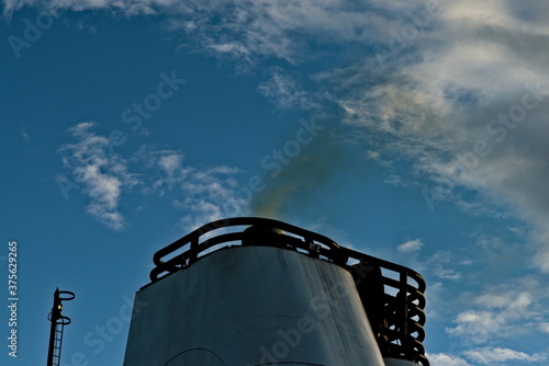 Black smoke coming out of the smokestack of a large ship. photo