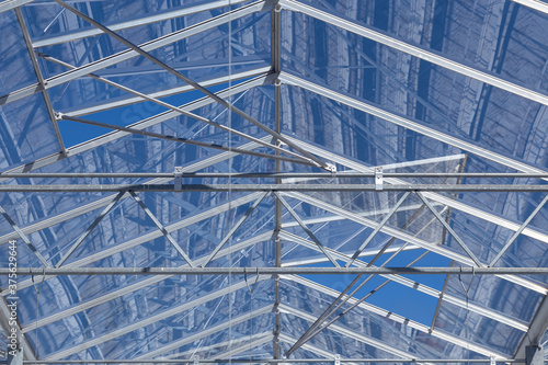 blue sky through the glass roof of an industrial greenhouse