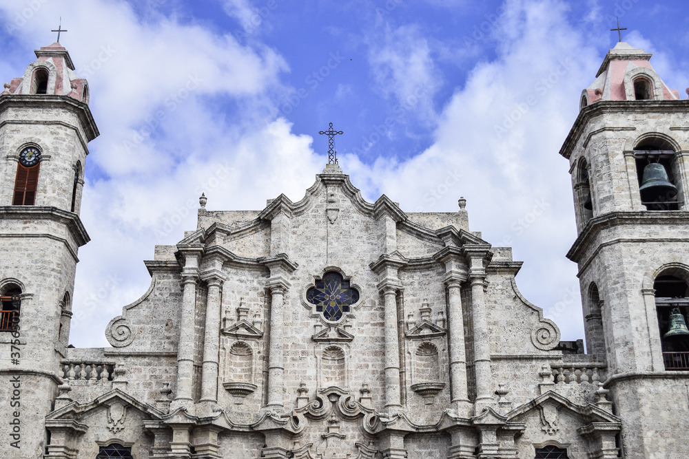 The facade of Havana Cathedral in Cuba. The sky is blue with some clouds.
