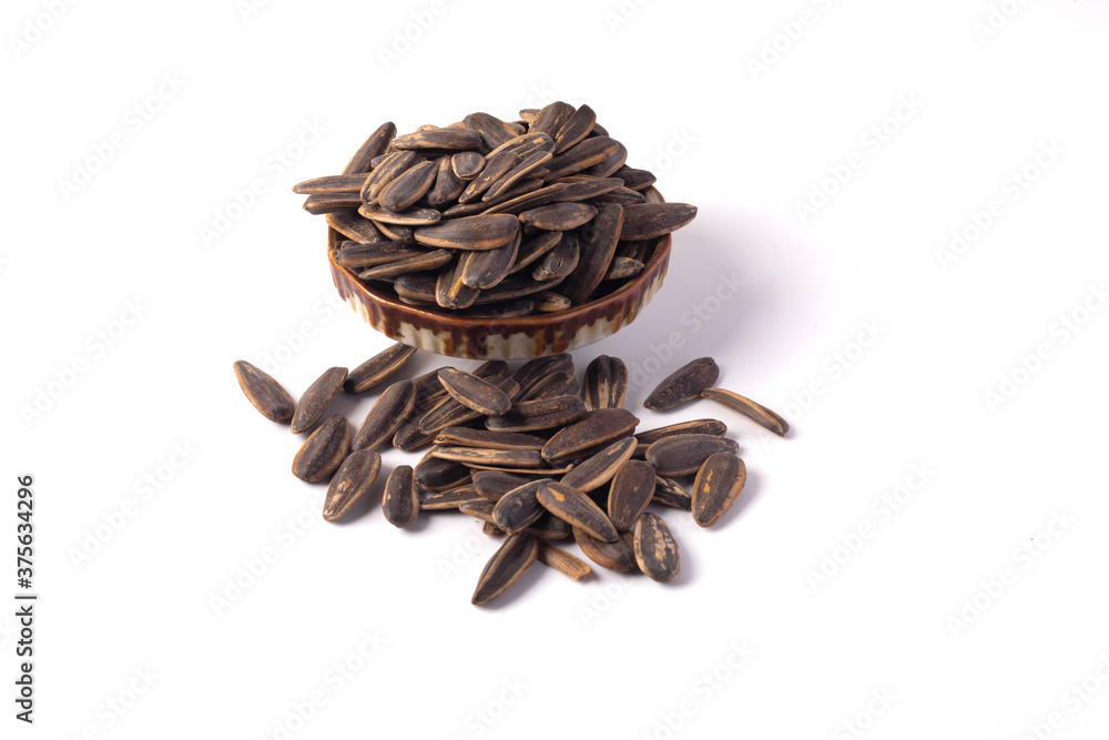 Dry sunflower seeds in a ceramic cup on a white background.