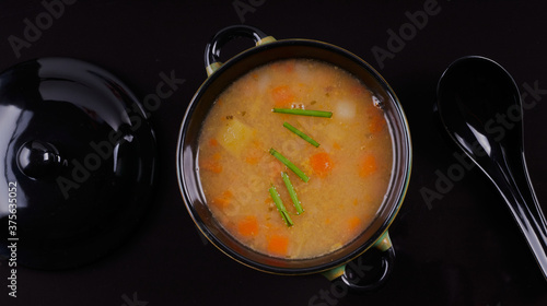 bowl of homemade broth on black background.