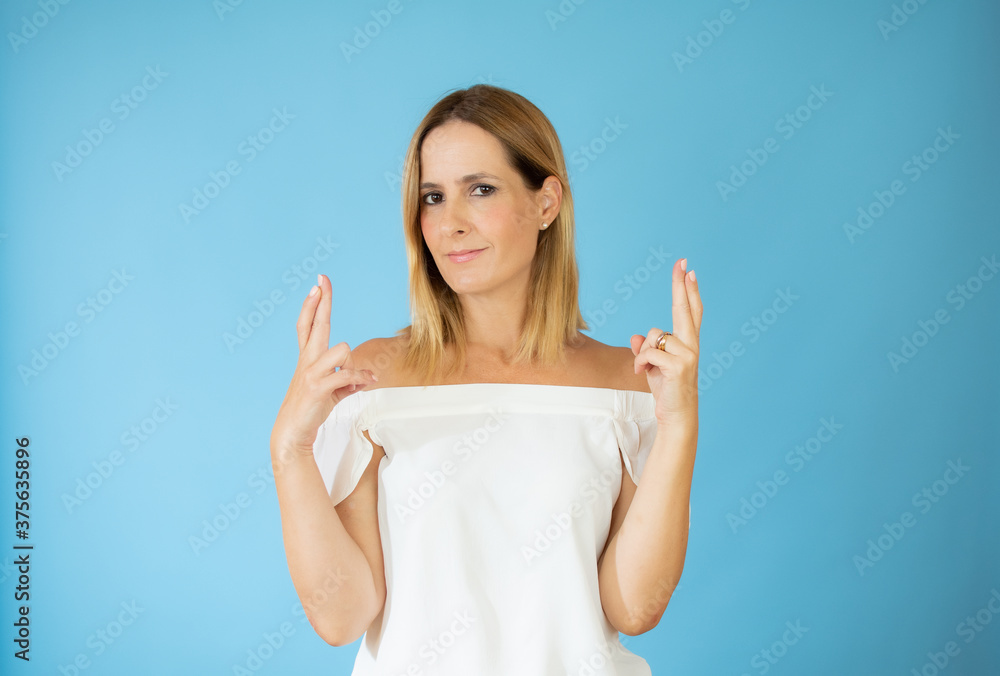 Beautiful woman in white shirt with fingers crossed gesture Beautiful woman in white shirt with fingers crossed gesture