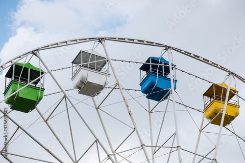 Carousel ferris wheel with colored cabins for children and adults to ride on day off.