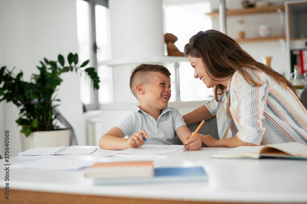 Mother helping her son with homework at home. Little boy learning at home.. Mother helping her son with homework at home. Little boy learning at home..