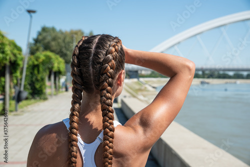 Close up of fit muscular fitness woman hair tied in braids for outdoor cross workout and training view from back photo