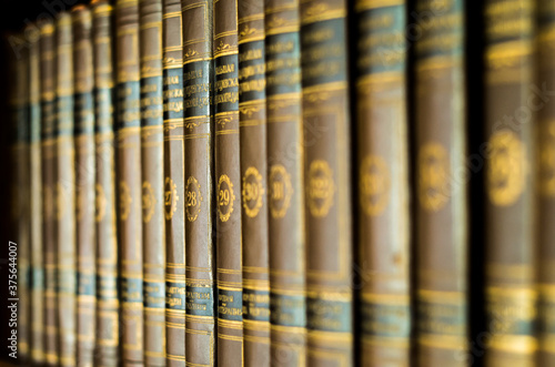 Bookshelf with volumes of old books with golden writings, encyclopedia