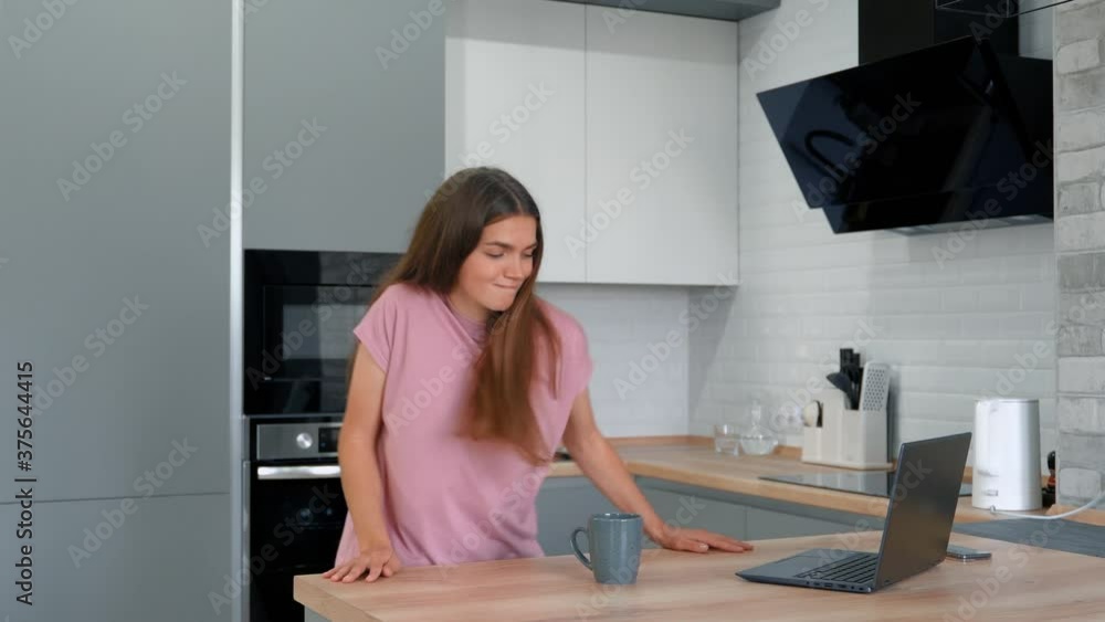 This video shows a teen girl playing a song on her laptop and dancing in her kitchen. This video shows a teen girl playing a song on her laptop and dancing in her kitchen.