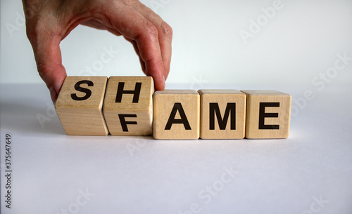 Hand turns cubes and changes the word shame to fame. Beautiful white background. Business concept. Copy space.
