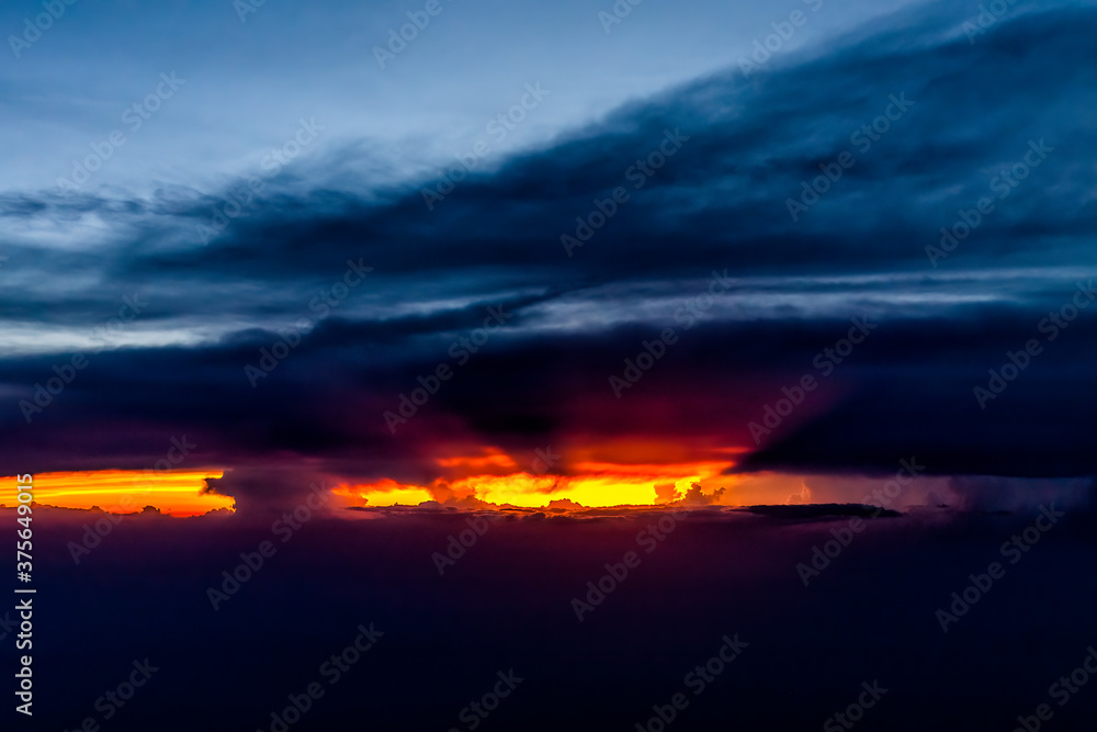 Colorful dramatic red dark sunset sun rays behind clouds in Virginia horizon high angle aerial view from airplane window from Dulles airport with skyscape