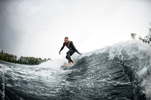 guy rides on surfboard down wave and touches the water