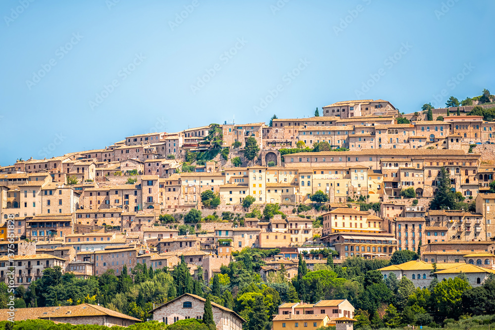 Town village city of Assisi in Umbria, Italy cityscape of buildings during summer day landscape with hilltop houses and blue sky