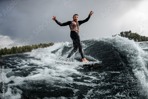 attractive man having fun rides wave on surfboard in the summer day
