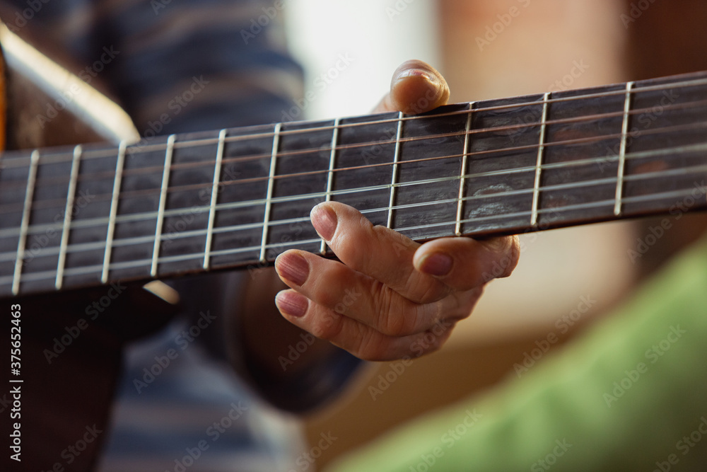 Senior woman playing guitar, close up hands, self-development. Caucasian woman spending time for new job or hobby, having fun, getting new profits. Music, art, creation concept, remote education.