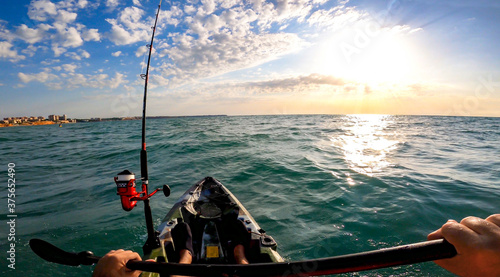 Принти на полотні Fisherman trolling in kayak at mediterranean sea on a windy day with waves during sunset