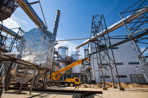 Shiny metal furnaces, tower, pipes, chemical equipment and yellow truck mobile crane. Kzylorda region, Kazakhstan.