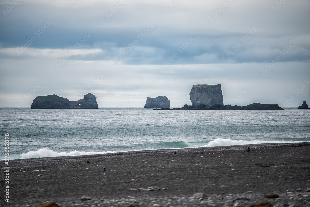 Vik, Iceland famous black sand beach sea horizon rock formation at Dyrholaey, Kirkjufjara on south coast with Atlantic ocean
