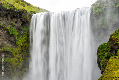 Skogafoss, Iceland dramatic waterfall closeup on cliff with green moss in summer with smooth long exposure motion of water
