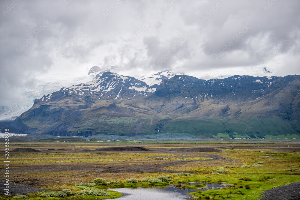 Landscape view on Skaftafell National Park, Iceland snow glacier with rocky cliffs snowcapped mountains and mist fog stormy clouds