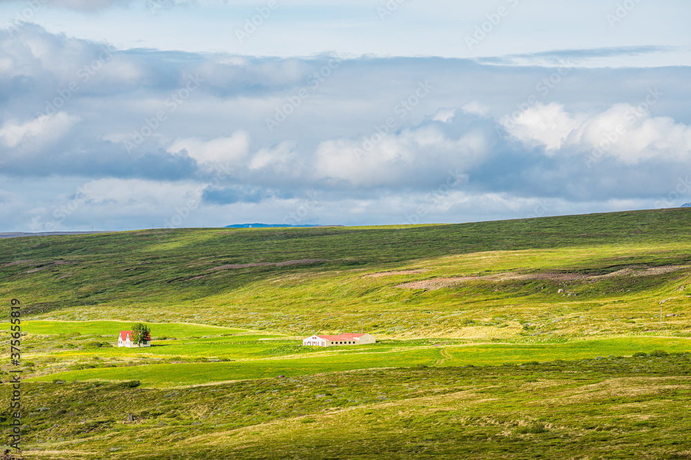 Landscape view of Iceland meadow open field near Skutustadagigar and lake Myvatn during cloudy sunny day and green grass hills with house in summer