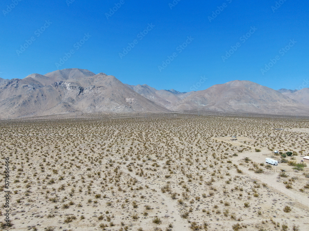Aerial view of desert hills under blue sky in California's Mojave desert, near Ridgecrest. Small rock formations, desert brush. Aerial view of desert hills under blue sky in California's Mojave desert, near Ridgecrest. Small rock formations, desert brush.