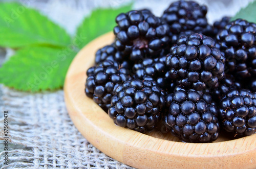 Freshly picked ripe blackberries on a wooden plate on the table.Healthy eating,vegan food or diet concept.Selective focus.