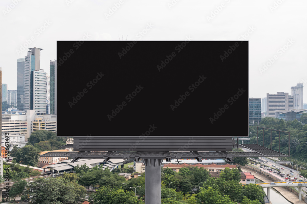 Fototapeta premium Blank black road billboard with Kuala Lumpur cityscape background at day time. Street advertising poster, mock up, 3D rendering. Front view. Concept of marketing to promote or sell services or ideas.