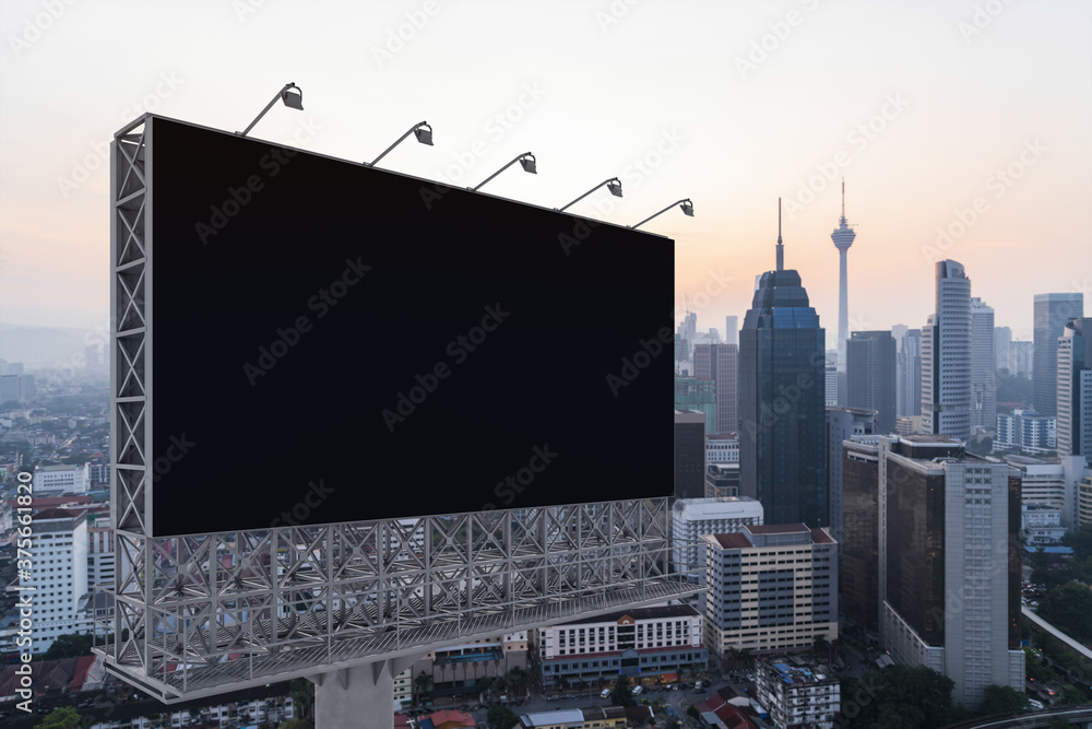Blank black road billboard with KL cityscape background at sunset. Street advertising poster, mock up, 3D rendering. Side view. The concept of marketing communication to promote or sell idea. Blank black road billboard with KL cityscape background at sunset. Street advertising poster, mock up, 3D rendering. Side view. The concept of marketing communication to promote or sell idea.