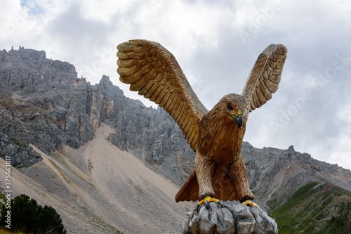 Wood sculpture of an eagle, symbol of South Tyrol, with the background of Dolomite peaks of Latemar mountain group. Predazzo, South Tyrol, Italy © Travelvolo
